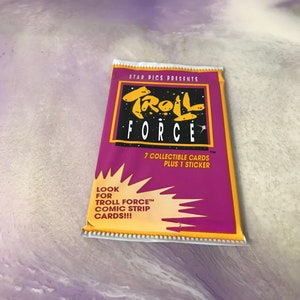 May include: A purple and yellow package for Troll Force collectible cards. The package features a cartoon troll with a star and the text "STAR PICS PRESENTS TROLL FORCE". The package includes 7 collectible cards and 1 sticker. The text "LOOK FOR TROLL FORCE™ COMIC STRIP CARDS!!!" is printed on the bottom of the package.