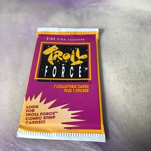 May include: A pink and yellow package of Troll Force trading cards. The package features a cartoon troll with the text "Troll Force" and "7 collectible cards plus 1 sticker". The package also includes the text "Look for Troll Force comic strip cards!!!"
