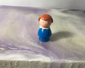 Figurka Fisher Price Little People z lat 60. i 70. XX wieku. Kobieta Fisher Price w brązowych włosach i niebieskim stroju. Figurka Little People