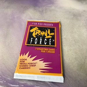 May include: A purple and yellow package of Troll Force collectible cards. The package features a cartoon troll with the text "Troll Force" and "7 collectible cards plus 1 sticker".