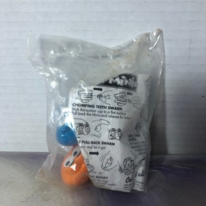 Könnte beinhalten: Ein Set mit zwei Rückziehauto-Charakteren mit Saugnäpfen. Die Figuren sind blau und orange mit Comic-Gesichtern. Die Verpackung enthält Anweisungen für "Kauen Zähne Schwarm" und "Zurückziehen Schwarm".