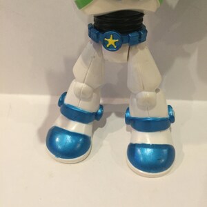 Pu&ograve; includere: Una action figure di astronauta bianca e blu con una stella gialla sulla cintura. La figura ha un casco blu e un corpo bianco con accenti blu.