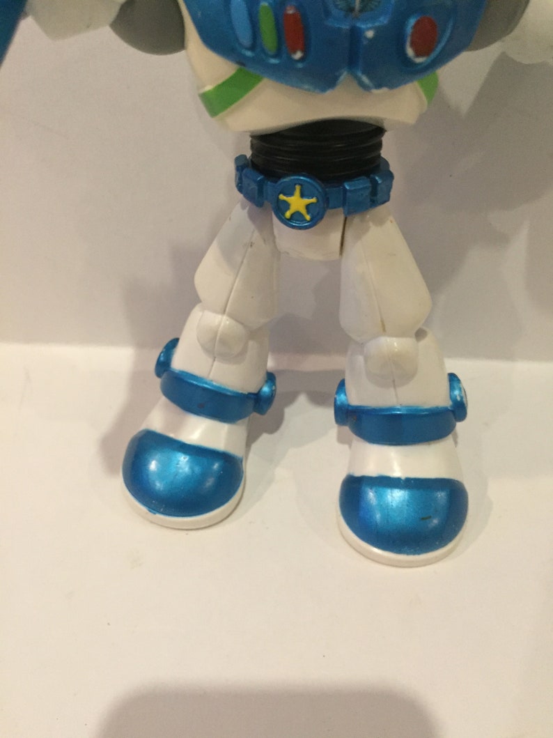 Pu&ograve; includere: Una action figure di astronauta bianca e blu con una stella gialla sulla cintura. La figura ha un casco blu e un corpo bianco con accenti blu.