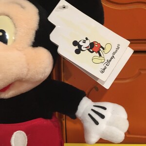 Puede incluir: Juguete de peluche Mickey Mouse negro y rojo con una etiqueta blanca que dice "Walt Disney World&reg;".