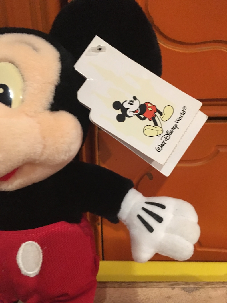 Puede incluir: Juguete de peluche Mickey Mouse negro y rojo con una etiqueta blanca que dice "Walt Disney World&reg;".