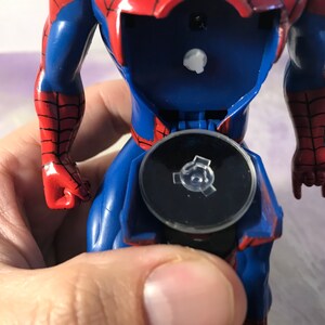 May include: A red and blue plastic action figure of Spider-Man with a black base. The figure is posed with one arm raised and the other arm bent at the elbow. The figure is missing a small piece from the base.