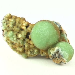 May include: A cluster of green and brown mineral specimens. The green mineral is a rounded, ball-shaped formation. The brown mineral is a rough, textured formation.