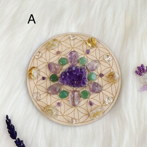 Könnte beinhalten: Ein Holzkreis mit einem Lebensblume-Muster und verschiedenen Kristallen, die in einem Kreis angeordnet sind. Die Kristalle sind Amethyst, klarer Quarz, grüner Aventurin und Citrin.