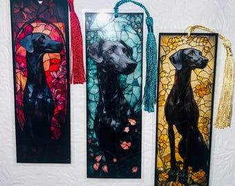 Könnte beinhalten: Drei rechteckige Lesezeichen mit schwarzen Hundeporträts in Buntglas-Designs. Jedes Lesezeichen hat eine andere Hintergrundfarbe: Rot, Blau und Gelb. Jedes Lesezeichen hat eine Quaste in einer passenden Farbe: Rot, Türkis und Gold.