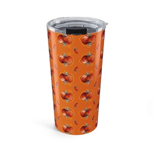 May include: A cylindrical stainless steel tumbler with a clear plastic lid and a black sliding closure. The exterior features a repeating pattern of orange-red cashew nuts on a vibrant orange background, creating a consistent graphic design.