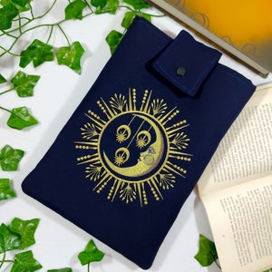 May include: A navy blue fabric pouch with a gold embroidered sun and moon design. The pouch has a flap with a snap closure.