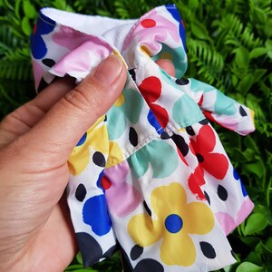 May include: A white dress with a colorful floral print. The dress has a ruffled hem and a white lining.