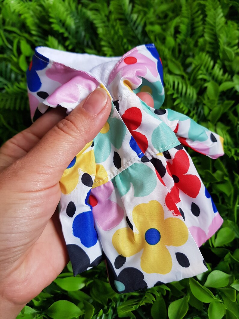 May include: A white dress with a colorful floral print. The dress has a ruffled hem and a white lining.
