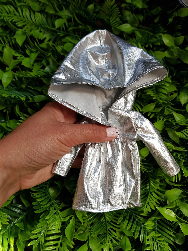 May include: A silver hooded jacket with a shiny metallic finish. The jacket has a zipper closure and long sleeves.