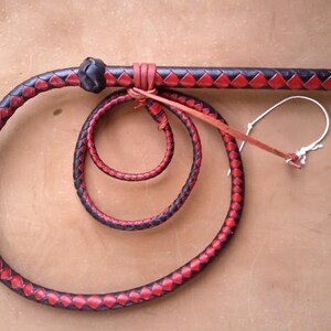 May include: A black and red leather bullwhip with a braided handle and a loop at the end.