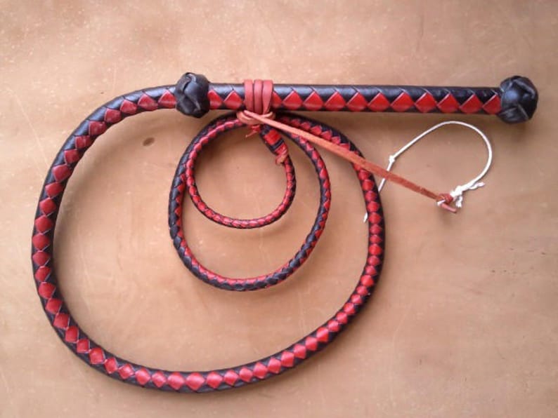 May include: A black and red leather bullwhip with a braided handle and a loop at the end.