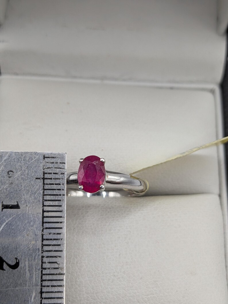 May include: A white ceramic mug with a black handle and the text "But First, Coffee" in a bold, black font. The mug is set against a blurred background, suggesting a cozy setting. The mug appears to be approximately 4 inches tall.