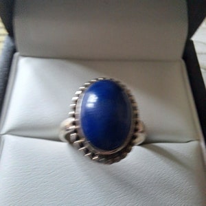 May include: A silver ring with a large, oval-shaped blue gemstone set in a decorative silver bezel.