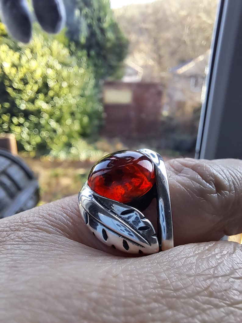 May include: A silver ring with a red gemstone set in a leaf design.