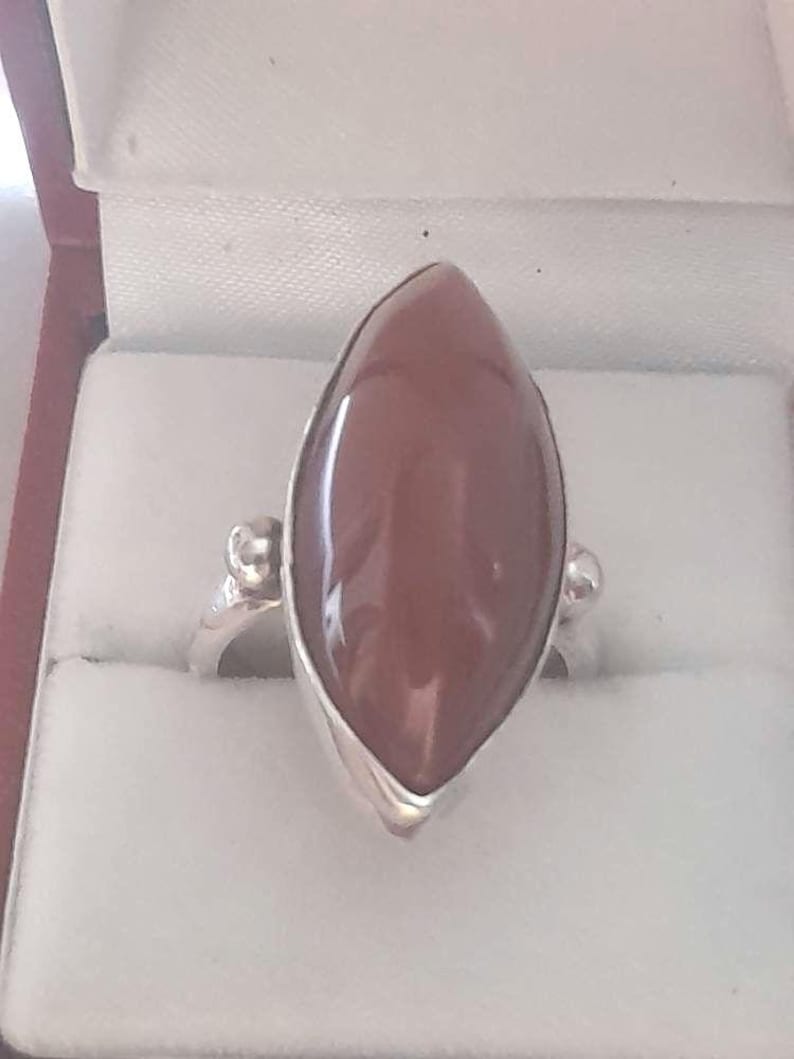 May include: A silver ring with a brown marquise-shaped gemstone.