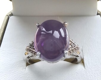 May include: A silver ring with a large, round, purple amethyst gemstone surrounded by smaller, clear gemstones.