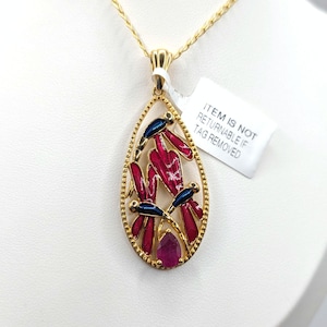 Puede incluir: Collar con colgante dorado con un colgante en forma de lágrima. El colgante presenta diseños de libélulas de esmalte rojo y azul y un rubí. La etiqueta dice: ITEM IS NOT RETURNABLE IF TAG REMOVED.