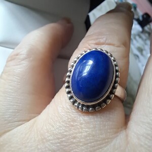 May include: A silver ring with a deep blue oval lapis lazuli gemstone set in a beaded bezel.