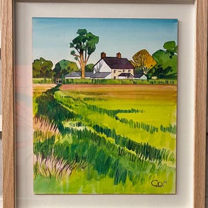 May include: A watercolor painting of a white farmhouse with a green roof, surrounded by trees and a field of green grass. The painting is framed in a light wood frame.