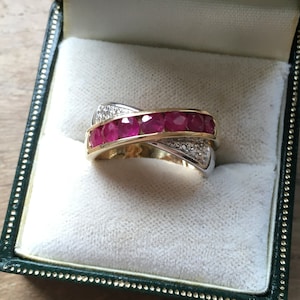 Pode incluir: Um anel de ouro e prata com uma fileira de rubis vermelhos e diamantes menores engastados na banda.