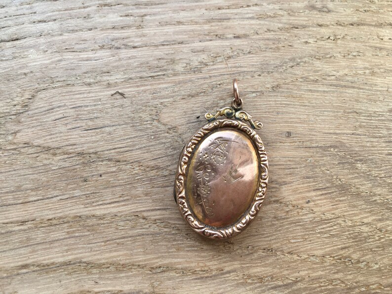 May include: A gold oval locket with an ornate design and a profile of a person engraved on the front.