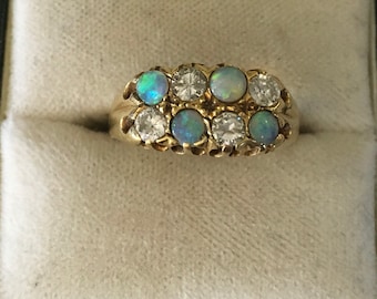 Op de afbeelding: Een gouden ring met een rij opalen en diamanten. De opalen zijn lichtblauwgroen van kleur en de diamanten zijn helder.