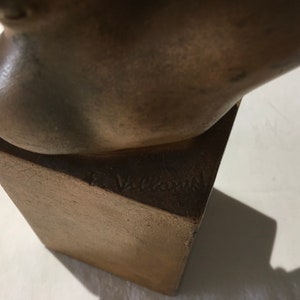 Op de afbeelding: Bronzen beeldhouwwerk van een hoofd op een vierkante basis. Het beeldhouwwerk is gesigneerd "F. Vallauri" op de basis.