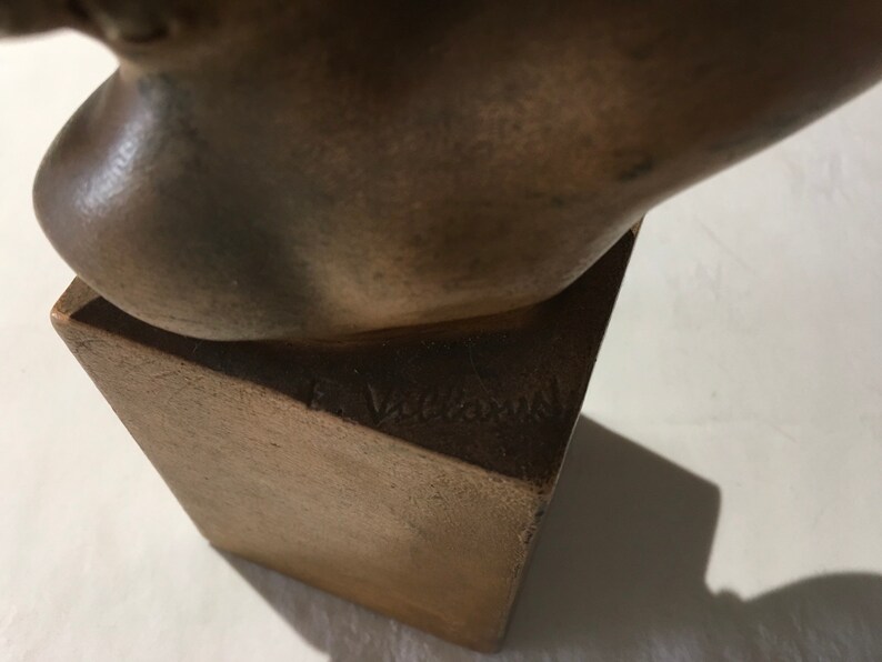 Op de afbeelding: Bronzen beeldhouwwerk van een hoofd op een vierkante basis. Het beeldhouwwerk is gesigneerd "F. Vallauri" op de basis.