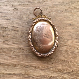 May include: A gold oval locket with an engraved design and the inscription "9CT & 18K MONT".