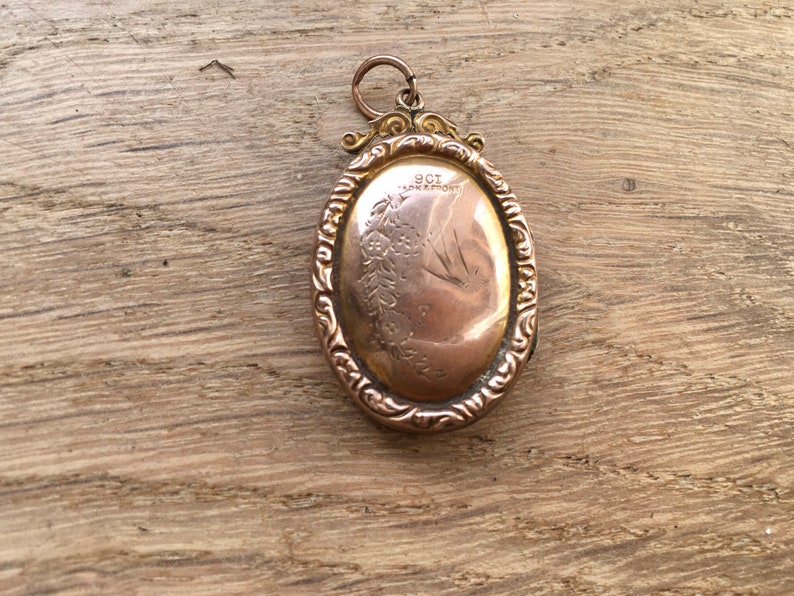 May include: A gold oval locket with an engraved design and the inscription "9CT & 18K MONT".
