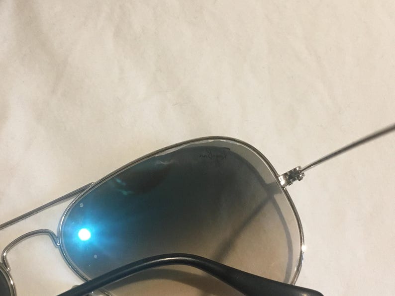 K&ouml;nnte beinhalten: Silberne Aviator-Sonnenbrille mit grauen Verlaufsgl&auml;sern. Die Sonnenbrille hat einen silbernen Metallrahmen und schwarze B&uuml;gel.