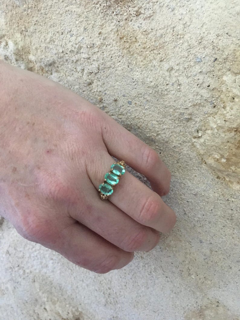 Pu&ograve; includere: Un anello d'oro con cinque pietre ovali di colore verde chiaro disposte in fila.