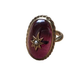 Antique gold and large cabochon garnet with split pearl in a gold star mount in the centre of the garnet