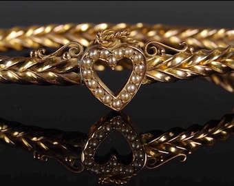 Brazalete antiguo victoriano de oro y perlas de semillas con bisagras y un corazón en el centro.