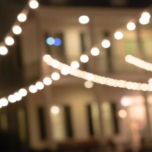 May include: A string of white lights strung across the front of a building, creating a warm and inviting atmosphere.