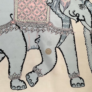 Op de afbeelding: Een lichtblauwe olifantenillustratie met zwarte contouren en decoratieve accenten. De olifant is versierd met roze en witte bloempatronen en sieraden. De achtergrond is cr&egrave;mekleurig.