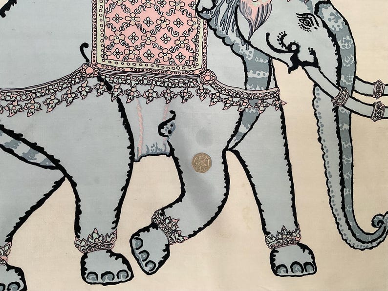 Op de afbeelding: Een lichtblauwe olifantenillustratie met zwarte contouren en decoratieve accenten. De olifant is versierd met roze en witte bloempatronen en sieraden. De achtergrond is cr&egrave;mekleurig.