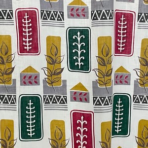 May include: A white fabric with a repeating pattern of green, red and gold stylised leaves and geometric shapes. The pattern is reminiscent of a traditional textile design.