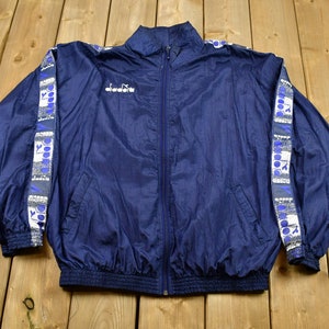 May include: A navy blue windbreaker jacket with white and blue trim on the sleeves and a white "Kappa" logo on the chest.