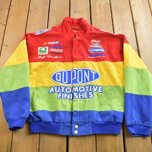 May include: A multi-coloured racing jacket with a rainbow stripe pattern. The jacket features the DuPont logo and the text "Automotive Finishes". The jacket also has several sponsor logos, including NASCAR, GMAC, Hendrick Motorsports, Pepsi, and Alka-Seltzer.