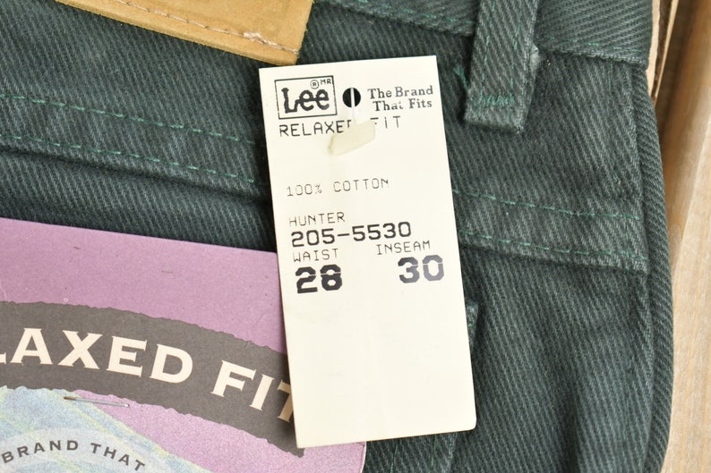 May include: A green pair of Lee Relaxed Fit jeans with a white tag that reads "Lee The Brand That Fits Relaxed Fit 100% Cotton Hunter 205-5530 Waist 28 Inseam 30".
