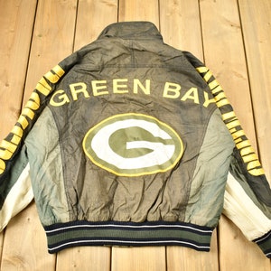 May include: Green Bay Packers jacket with a green and yellow logo on the back. The jacket has a black and white striped waistband and cuffs.