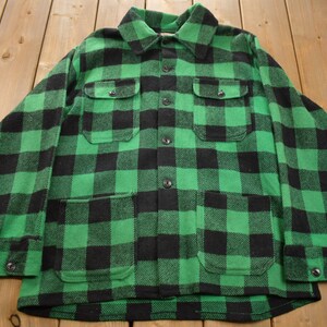 Puede incluir: Una camisa de franela a cuadros verde y negro con mangas largas y dos bolsillos en el pecho.