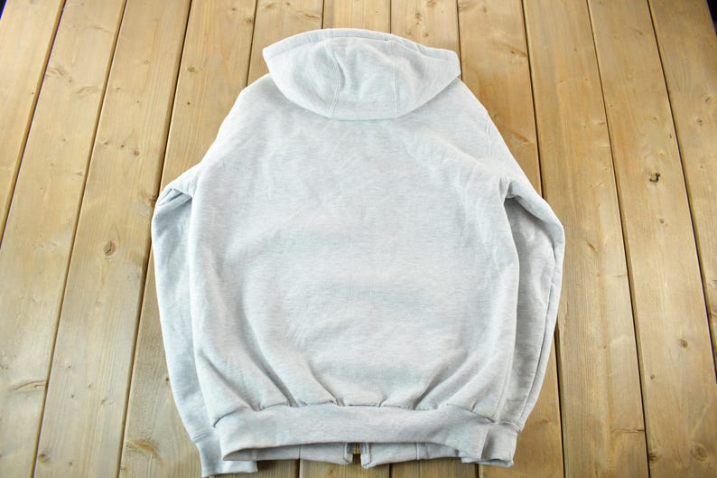 Puede incluir: Sudadera con capucha gris claro con cierre de cremallera completo. La vista trasera de la sudadera muestra la capucha, la cremallera y el dobladillo y los pu&ntilde;os de canal&eacute;. La sudadera est&aacute; hecha de un material suave y c&oacute;modo.