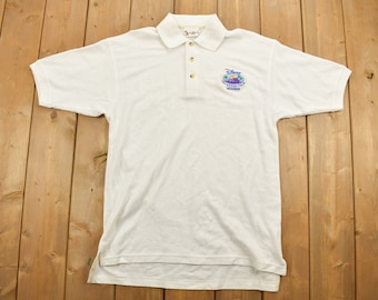 May include: White polo shirt with a Disney Vacation Club Member embroidered logo on the left chest.